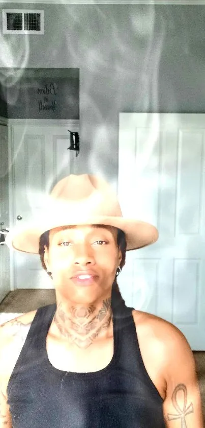 Portrait with hat and tattoos in smoky room.