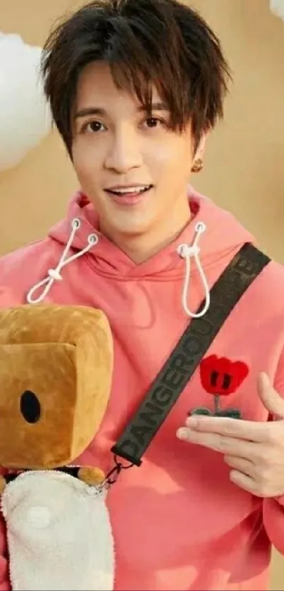 A trendy guy in a pink hoodie with plush toy and cloud background.