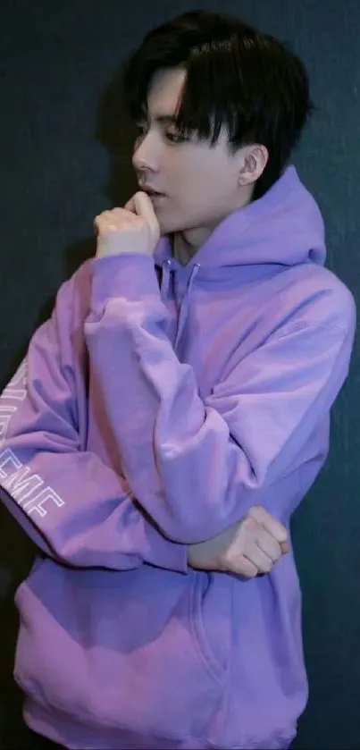 Person in purple hoodie posing against a dark background.