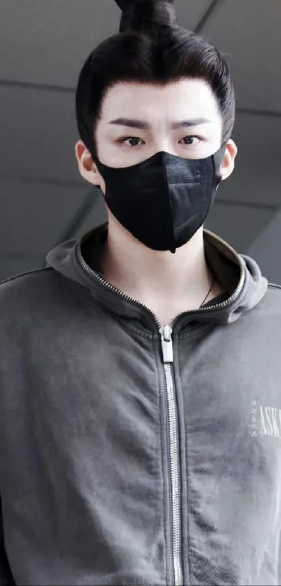 Person wearing grey hoodie and black mask, stylish and modern.