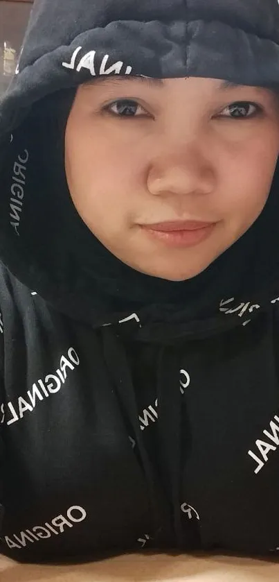 Person wearing a black hoodie with white text print.