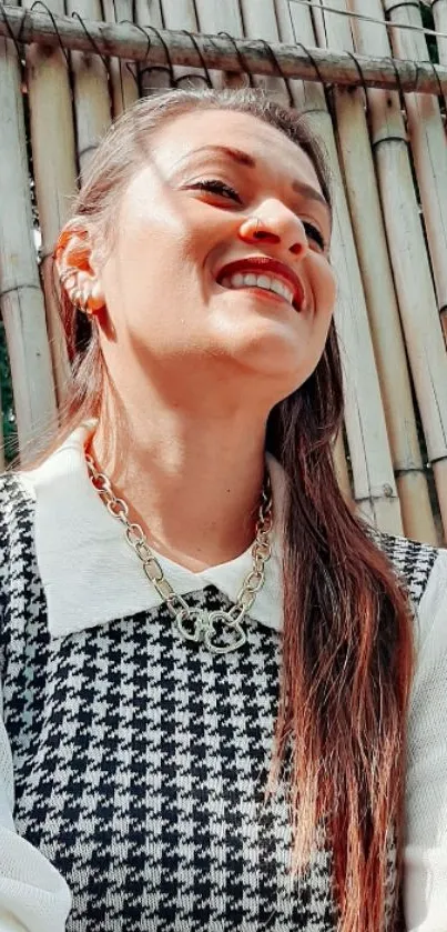 Woman in houndstooth attire with bamboo background, smiling elegantly.