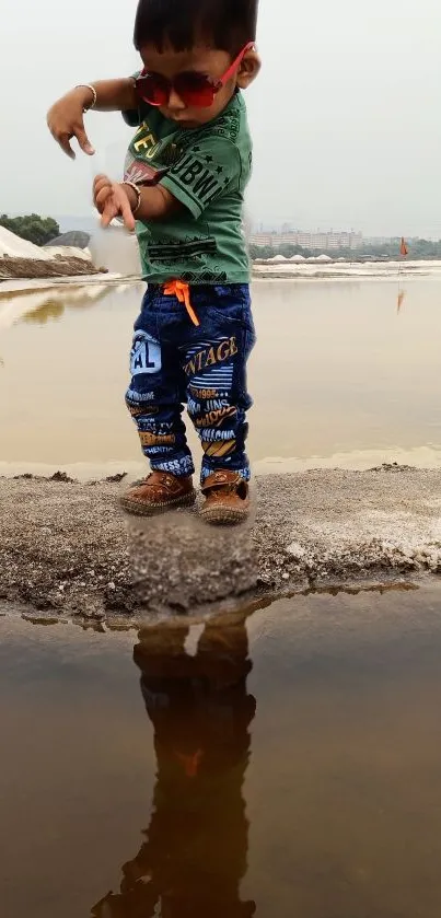 Child in sunglasses, reflecting by a pond.