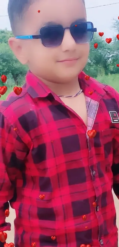 Child in red checkered shirt with sunglasses outdoors.