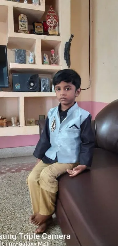 Child in a stylish outfit sitting on a brown couch in a cozy room.