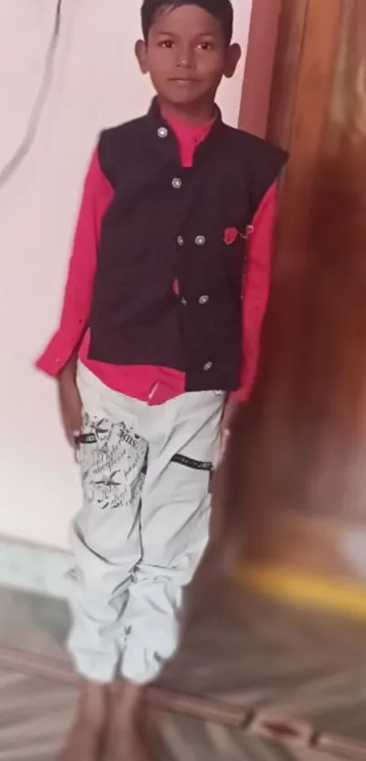 A young boy poses stylishly in a room with a wooden door backdrop.