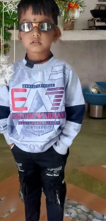 Young boy in stylish outfit with sunglasses indoors.