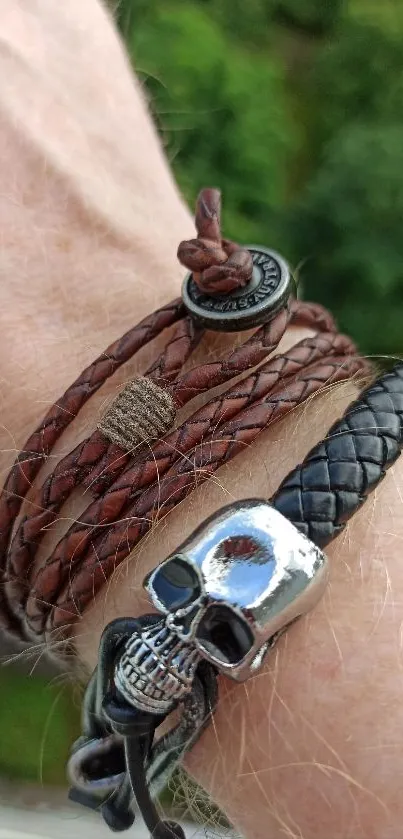 Close-up of stylish leather bracelets with a skull pendant on wrist.