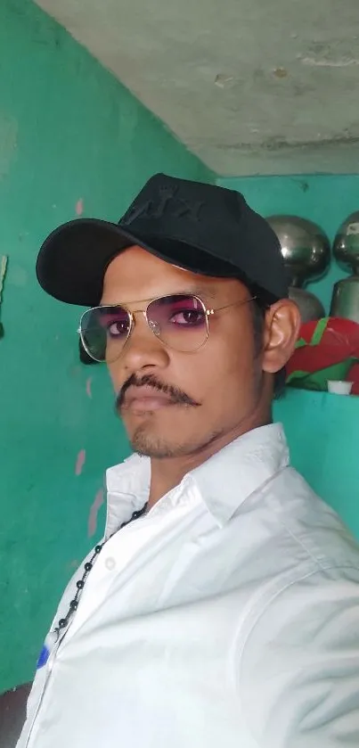 Man in sunglasses and cap, turquoise background.