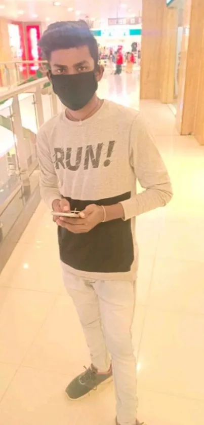 Young man in casual attire at a brightly lit mall.