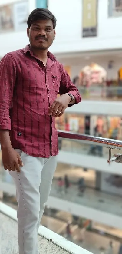 Person in a red shirt posing stylishly in a modern mall setting.