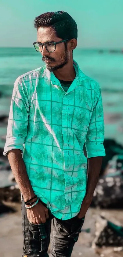 Man in turquoise shirt at ocean shore, stylish wallpaper.