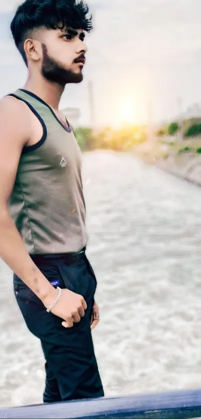 Stylish man standing by the riverside at sunset.