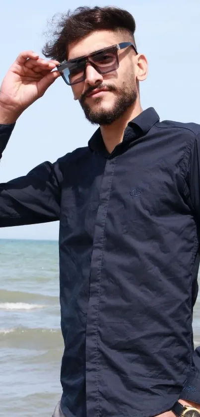 Man in navy shirt and sunglasses by the beach.