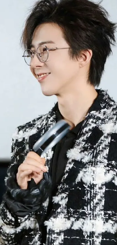 Man in checkered jacket holding a microphone, smiling.