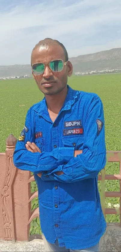 Man in blue shirt stands in vibrant green field.