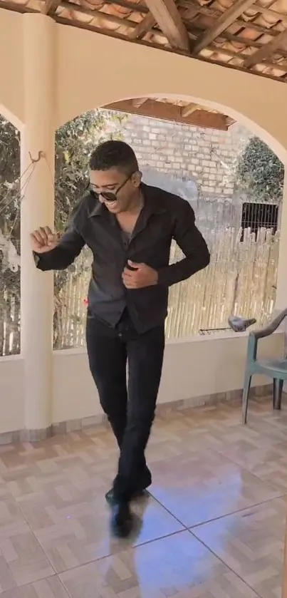 Stylish man in black outfit on a modern patio.