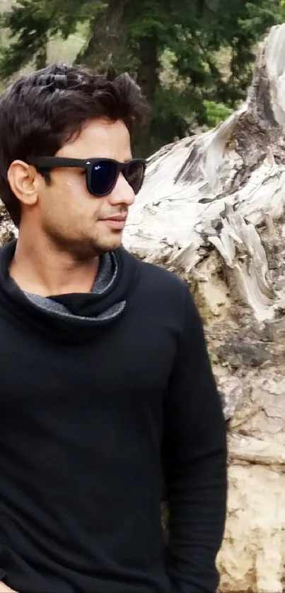 Man in black attire with sunglasses in nature.