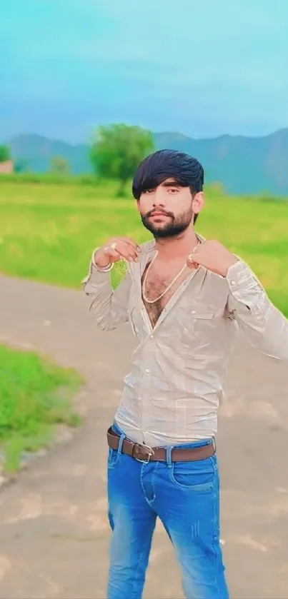 A stylish man poses outdoors with a scenic green backdrop.