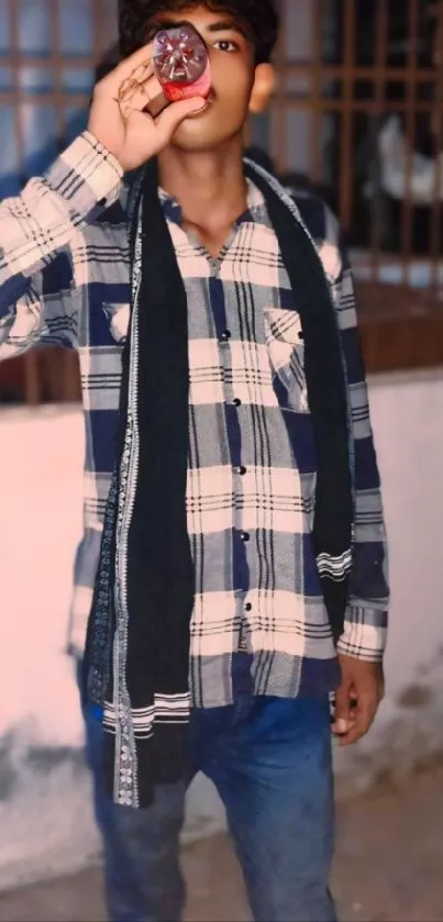 Young man in plaid shirt drinking a beverage.