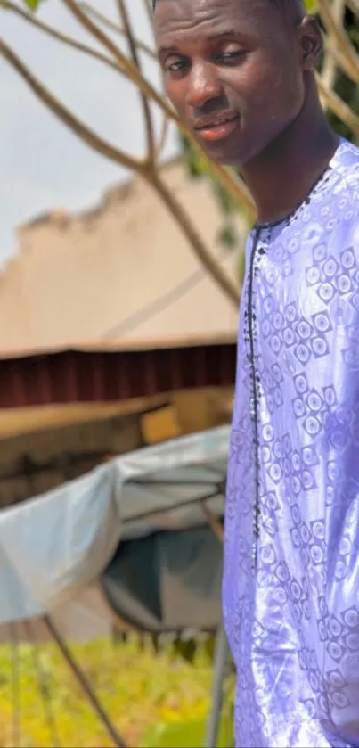 Man posing in stylish purple patterned outfit outdoors.