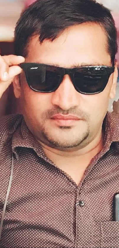 Stylish man wearing sunglasses with a smartphone in shirt pocket.