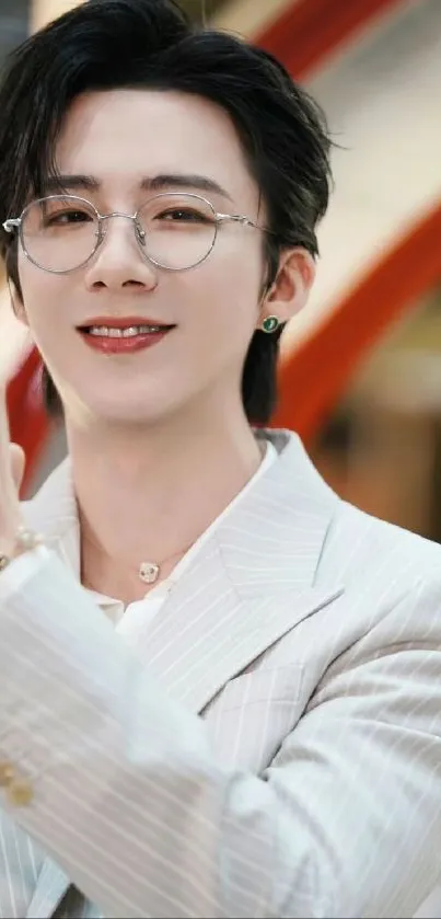 Man in a white suit with glasses and a friendly smile.