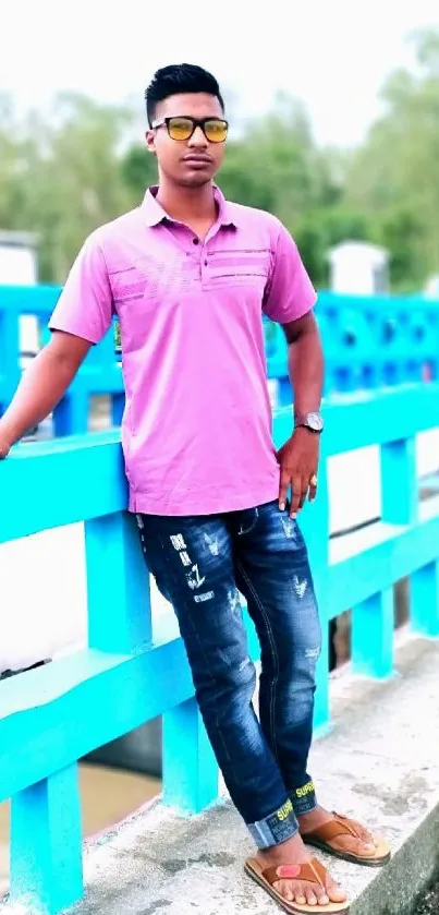 Stylish man in sunglasses on a vibrant blue bridge.