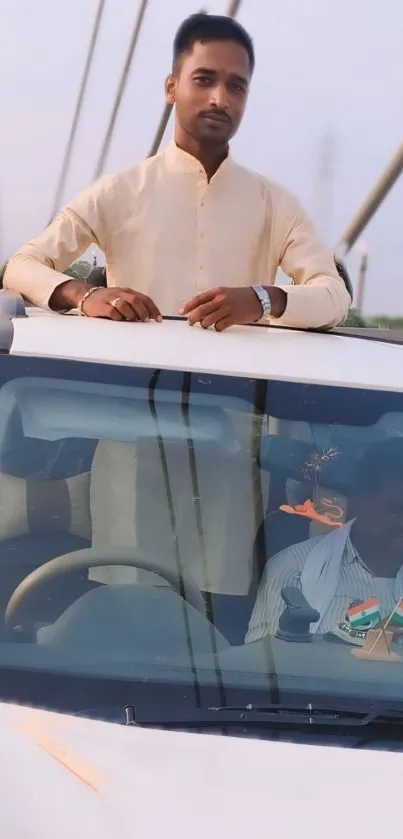 Man standing through car sunroof on a bridge.