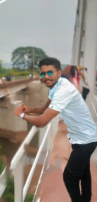 Man in sunglasses posing on a scenic bridge.