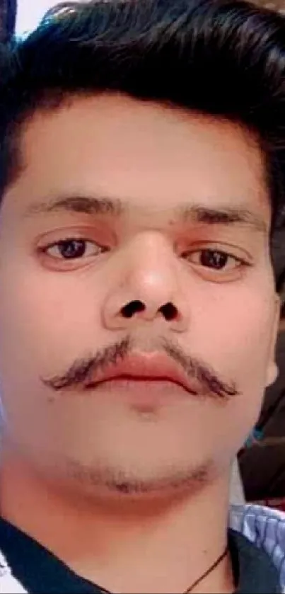 Portrait of a stylish man with a unique mustache posing indoors.