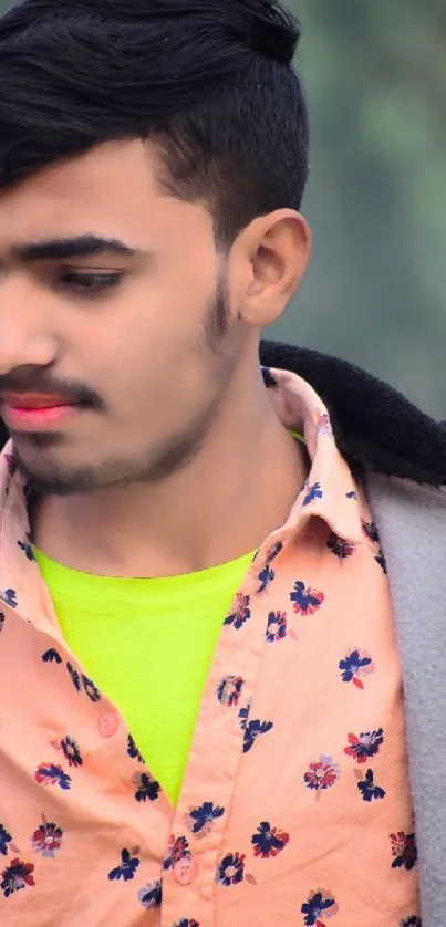 Young man in peach floral shirt posing outdoors with a confident look.