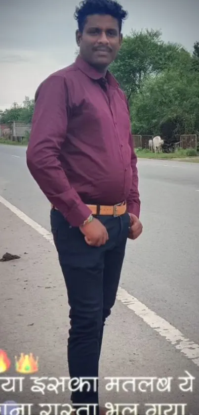 Man in burgundy shirt by roadside nature.