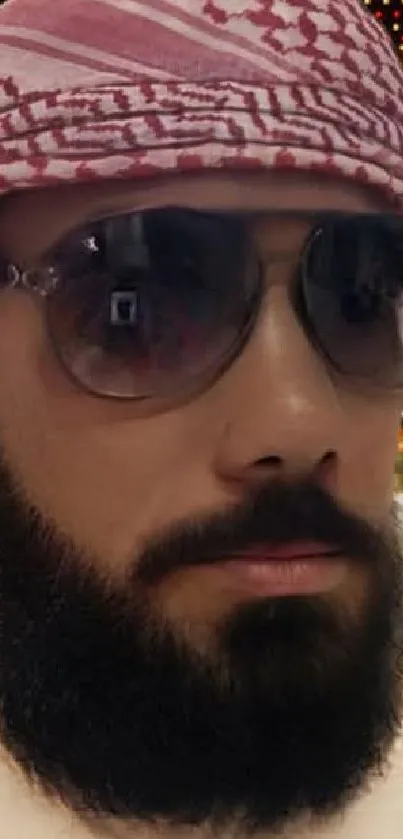 Bearded man wearing sunglasses and a keffiyeh at night.