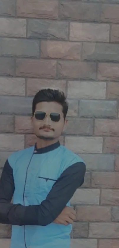 Man in sunglasses with brick wall backdrop, showcasing urban style.