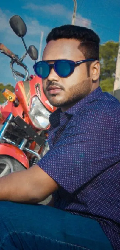 Man in sunglasses leaning against a red motorcycle.