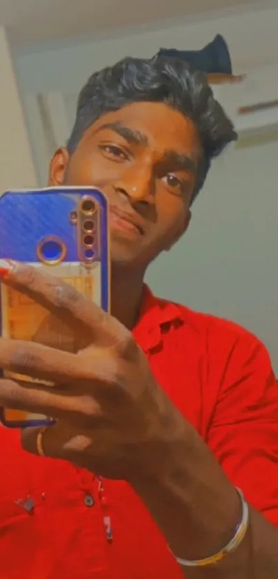 Stylish selfie with a red shirt and sleek smartphone.