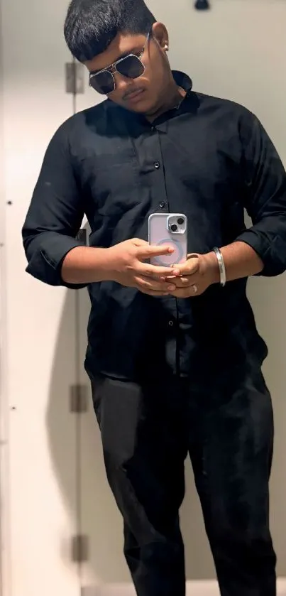 Stylish individual taking a mirror selfie in black attire.