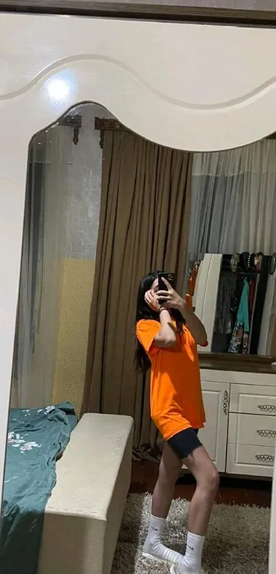 A stylish mirror selfie in an orange outfit, perfect for phone wallpaper.