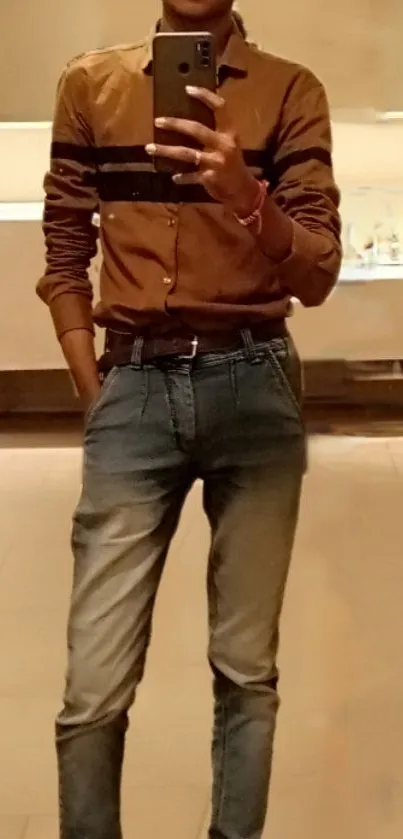 Mirror selfie with brown shirt and denim jeans in a relaxed setting.