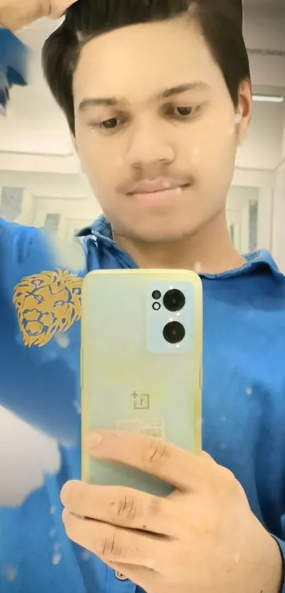 Young man taking selfie in mirror with blue shirt and smartphone.