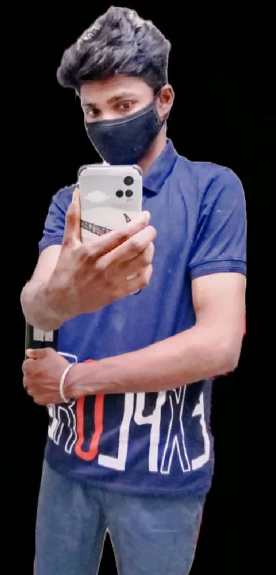 Young man in blue shirt taking a selfie against black background.