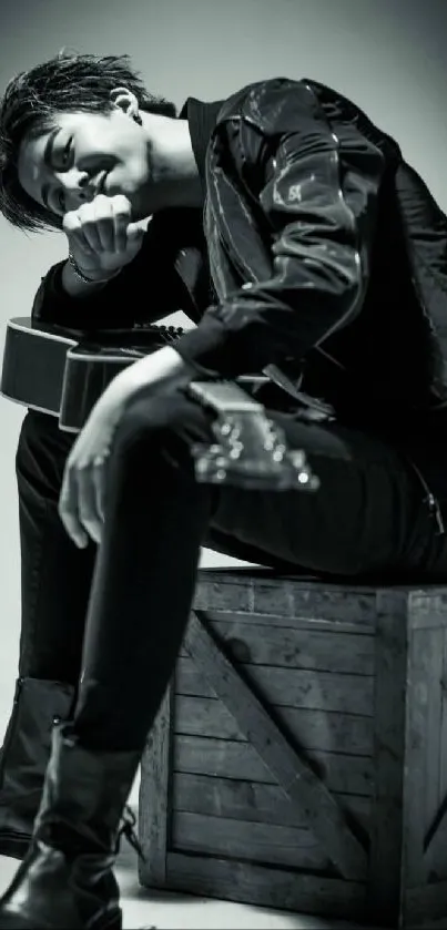 Stylish monochrome portrait with guitar, seated on a crate, in black and white.