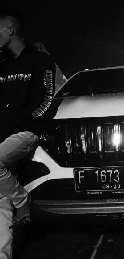 Monochrome image of a person standing with a car at night.