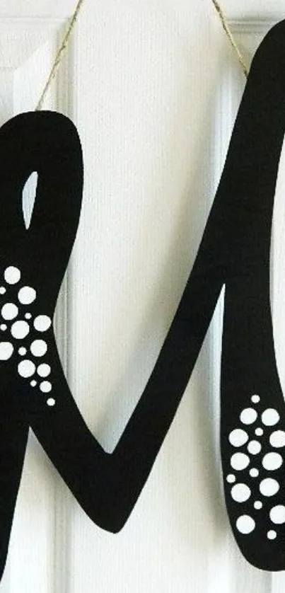 Stylish black monogram with white dots against white background.