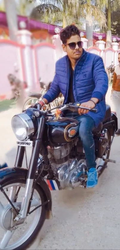 Man wearing blue jacket riding a classic motorcycle.