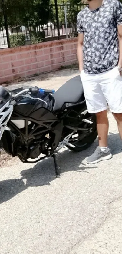 Man standing next to black motorcycle on urban street.