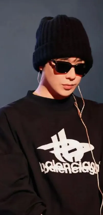 Person in black attire with headphones and beanie, wearing sunglasses.