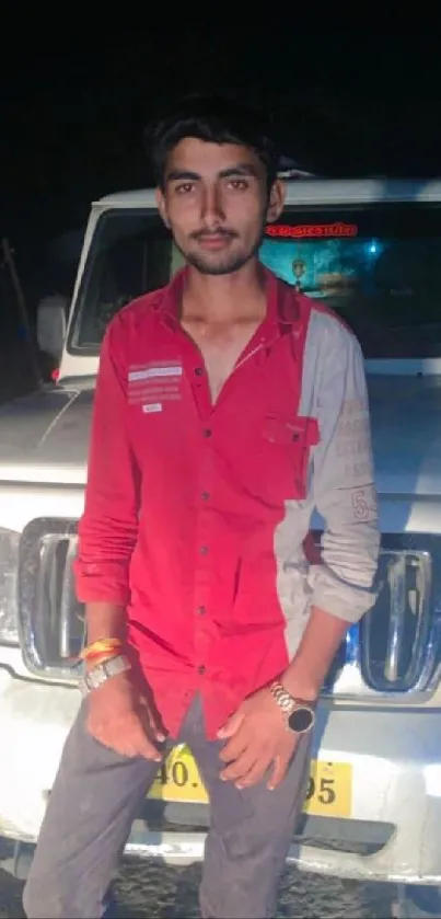 Man stands confidently in front of SUV at night.