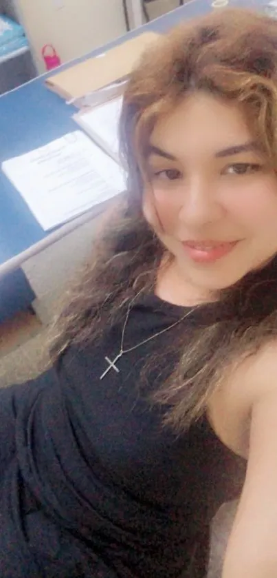 Stylish woman in black dress at office desk.